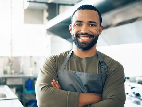 Dono de restaurante sorrindo em sua cozinha